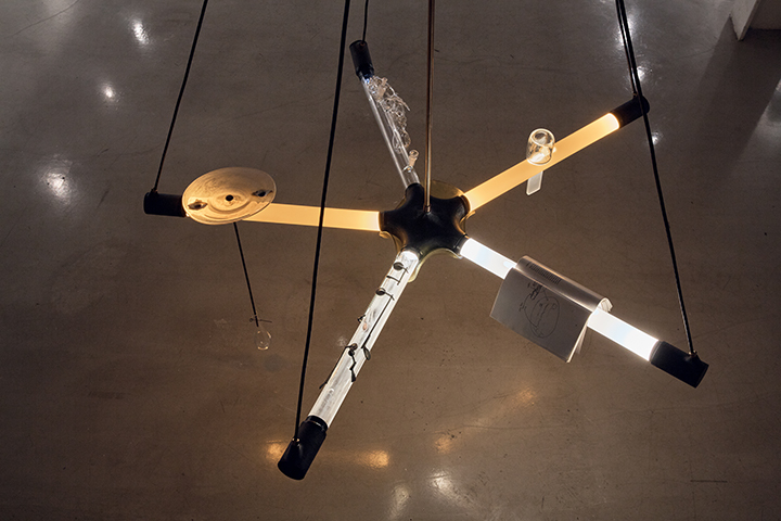 Ritual Chandelier, 2019, blown, slumped, cut, fused and torched glass, borosilicate, metal, oboe parts (from FBooth),Simone Forti's Handbook in Motion, paint, 9'x6'x10' (metalwork by Charles Mathis, coldwork by Ethan Stern, dragon by Sibelle Yuksek, lighting Neptune Glassworks, help from Romina Gonzales); installed in "Drawing Out Time" at UrbanGlass, Brooklyn, NY (curated by Alexis Wilkinson). Photography by Blaine Davis Studio